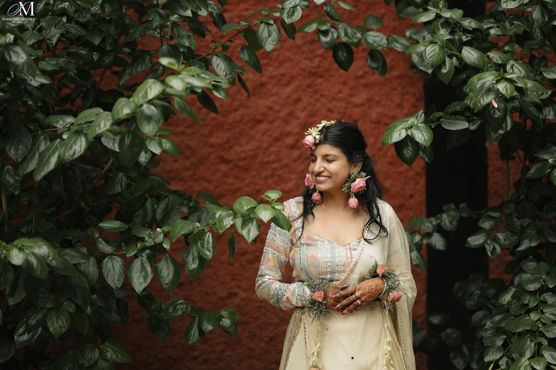 A woman in traditional indian attire stands amidst foliage.