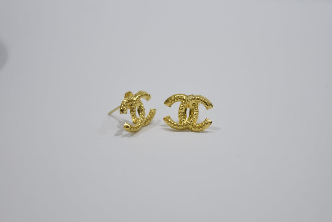 Gold interlocking cc logo earrings on white background