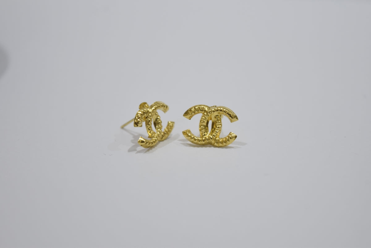 Gold interlocking cc logo earrings on white background