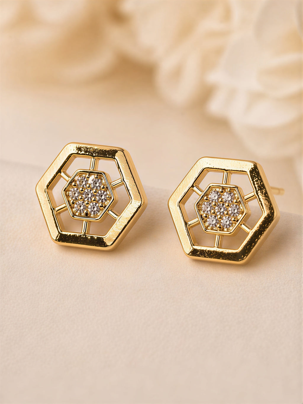 Close-up of gold plated hexagon stud earrings with sparkling stones, stylish geometric design for women